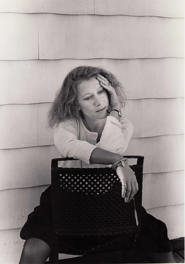 Black-and-white portrait of Helen Mirren sitting backwards on a chair, resting her head on one hand.